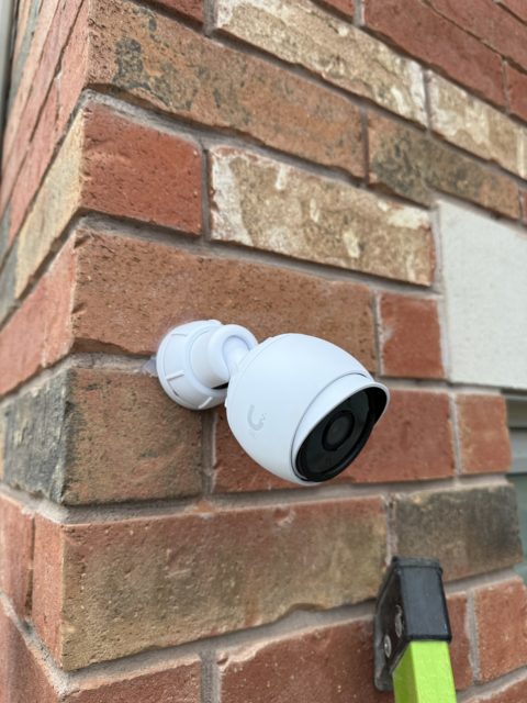 White security camera mounted on an exterior brick wall