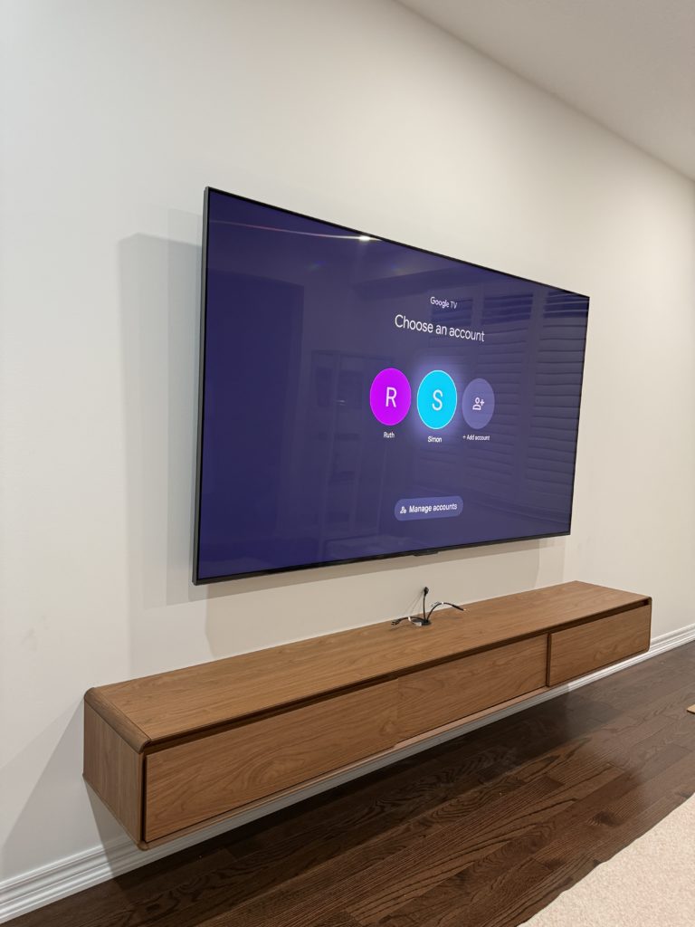 Wall-mounted TV above a floating wood media cabinet by Hamilton Tech Source