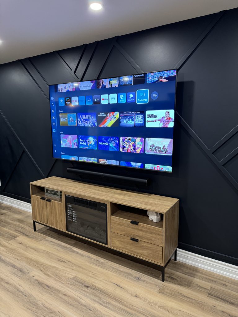 Large TV installed against a dark geometric feature wall by Hamilton Tech Source