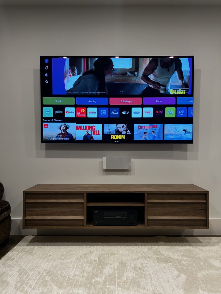 Wall-mounted TV above a wood media console by Hamilton Tech Source
